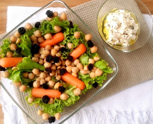 Salada com mini cenouras, grão de bico, uvas passas e coalhada seca temperada